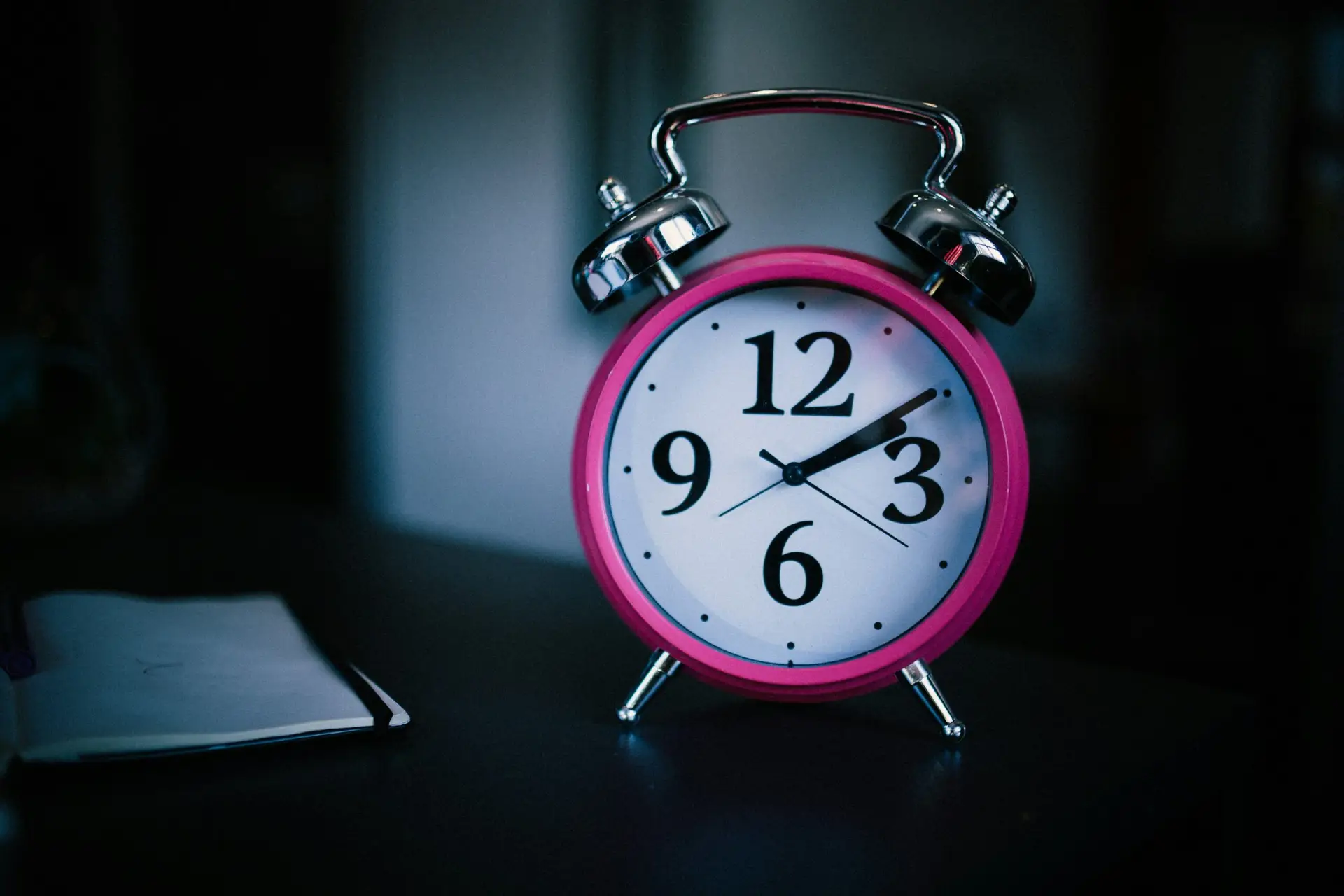 Réveil rose sur fond sombre illustrant les difficultés de sommeil accompagnées par le neurofeedback dynamique NeurOptimal®